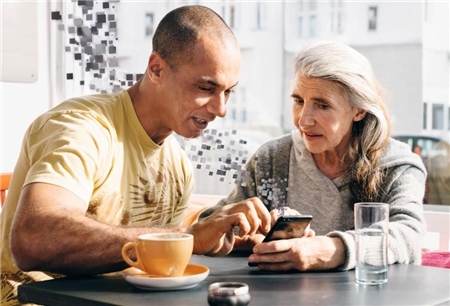 Smartphone-Cafe UP Ein junger Mann mit Migrations-Hintergrund erklärt einer Seniorin ihr Smartphone.