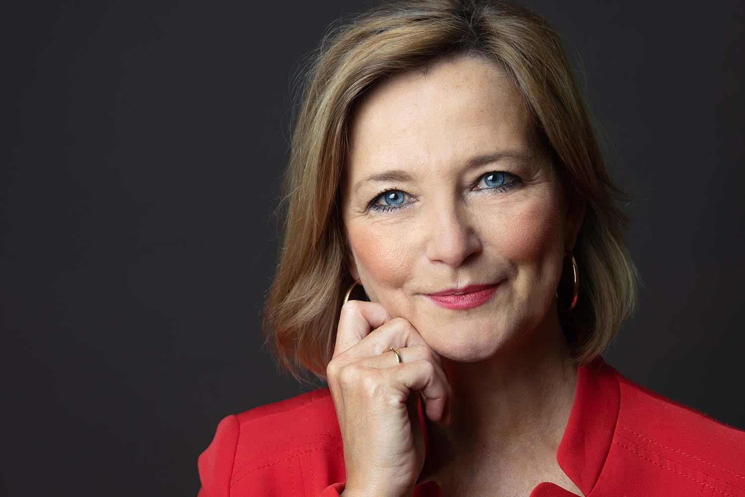 eine Frau mit kurzem Haare schaut in die Kamera und lächelt.