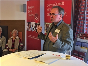 Manche suchen die Herausforderung Ein Mann steht an einem Stehpult und hält eine Rede