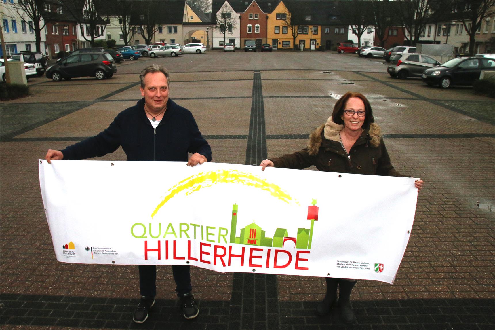 auf dem Bild stehen eine Frau und ein Mann und halten ein Banner