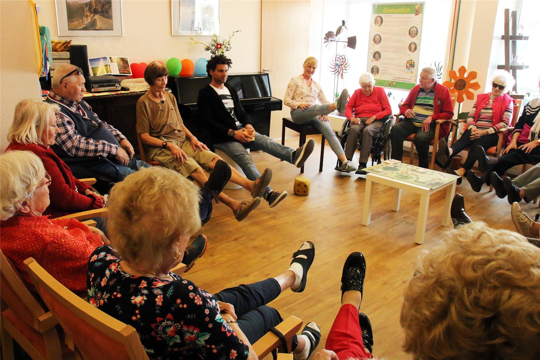 Auf dem Foto sitzen mehrere Menschen und spielen mit einem Ball