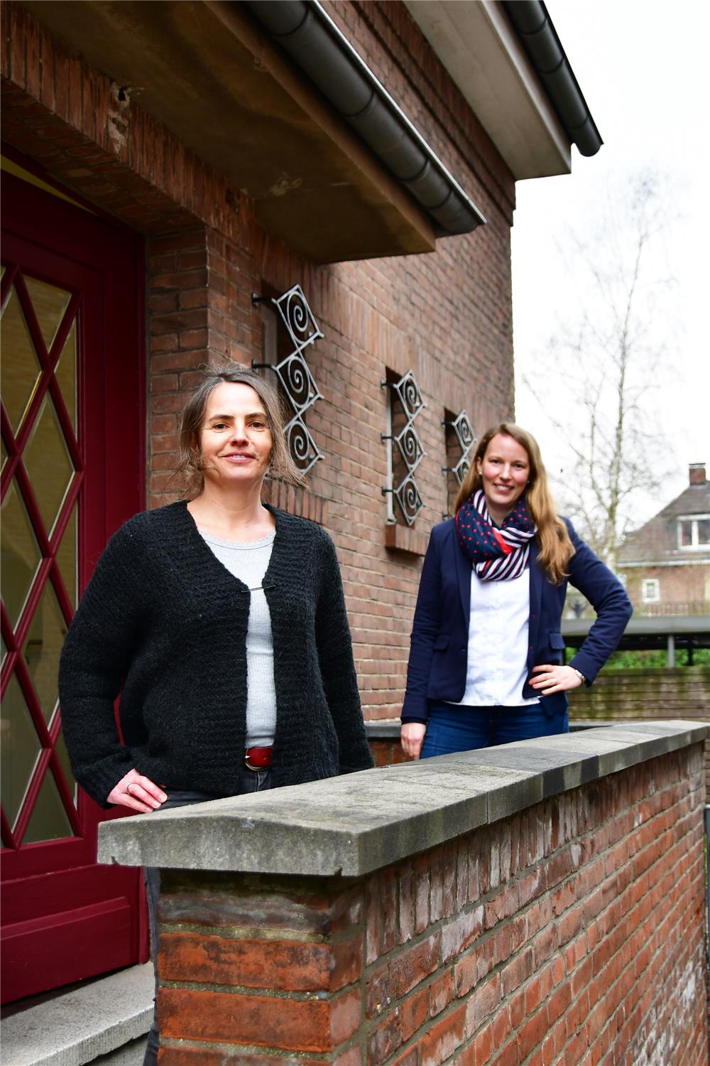 Das Foto zeigt zwei Frauen auf einer Treppe vor einem Gebäude.