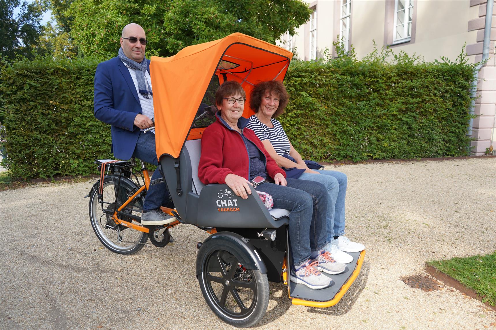 Oliver Höche, Leiter des Seniorenwohnhauses am Kurpark, steuert einen Zweisitzer, auf dem die Caritaskonferenz-Vorsitzende Karola Durgeloh und Susanne Koch, Platz genommen haben.