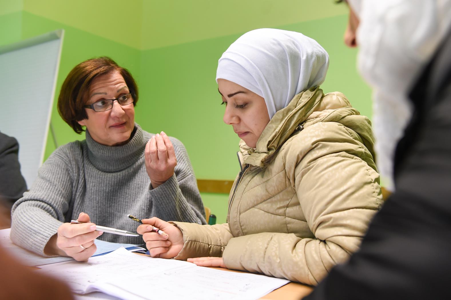 Caritas-Mitarbeiterin berät eine Ausländerin, die ein Kopftuch trägt