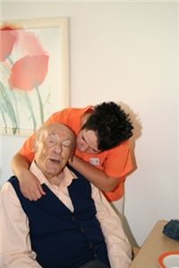 Betreuung Wir sehen eine Pflegekraft, die mit einem Heimbewohner redet.