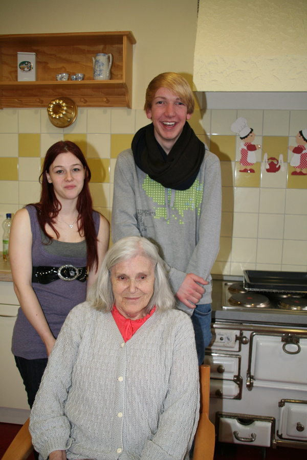 Zusehen ist das Kochteam mit zwei Jugendlichen und einer Bewohnerin des St. Marien Heimes. Sie haben sich vor dem Herd positioniert. 