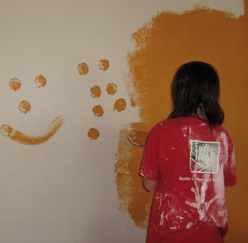 Eine Jugendliche beim Streichen der Wand