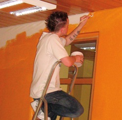 Ein Jugendlicher beim Streichen einer Wand