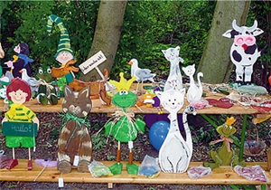 Viele Produkte aus den Werkstätten wurden zum Verkauf angeboten Auf einem Tisch und einer Bank stehen verschiedene bunt bemalte Laubsägenarbeiten in Tierform