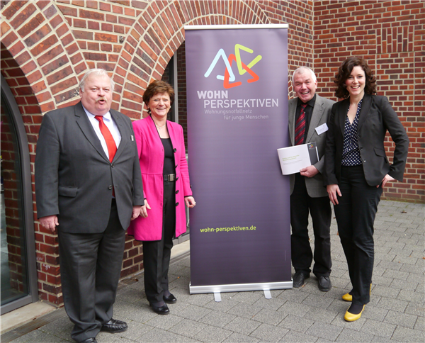 Auf dem Foto stehen vier Personen vor einem Banner.