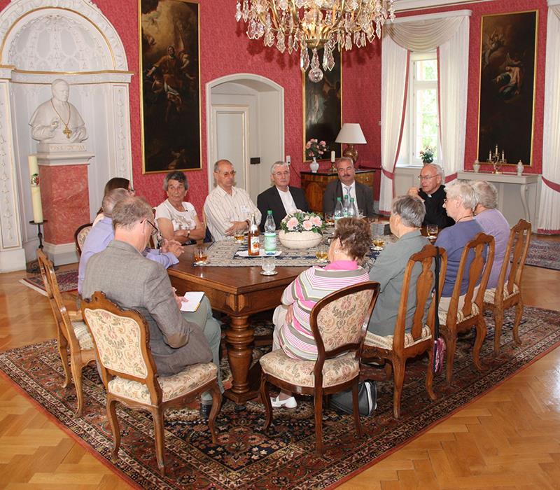 Wir sind beim Bischof Algermissen zu Gast. In einem großen hohen Raum haben sich alle Teilnehmer um einen großen Holztisch versammelt. Unser Bischof hat an der Stirnseite des Tisches Platz genommen. 