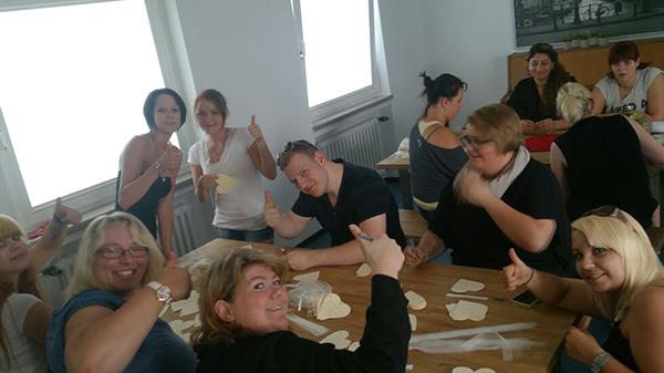 Wir sind zu Gast in der Altenpflegeschule. Die Schülerinnen und Schüler sitzen an Tischen und beschreiben ausgeschnittene Herzen. Alle unterbrechen ihre Arbeit und heben freudig ihren Daumen nach oben. 