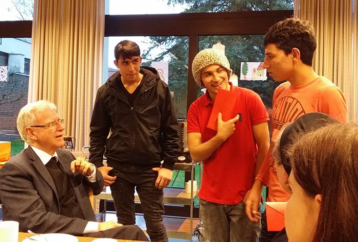 Unser Generalvikar sitzt am Tisch und wendet sich drei Flüchtlingen zu. Sie kommunizieren miteinander. 