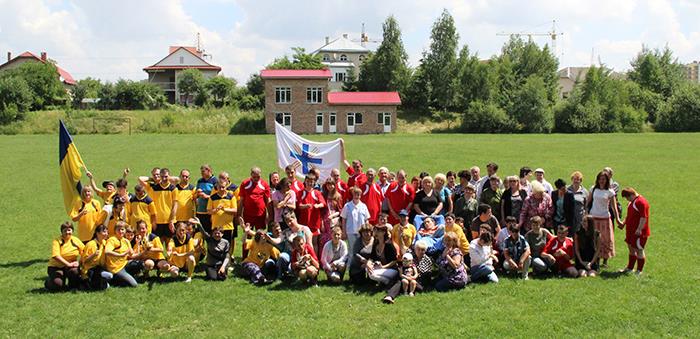 Wir sehen eine große Gruppe von Spielern und Zuschauern vor einem Fußballtor.