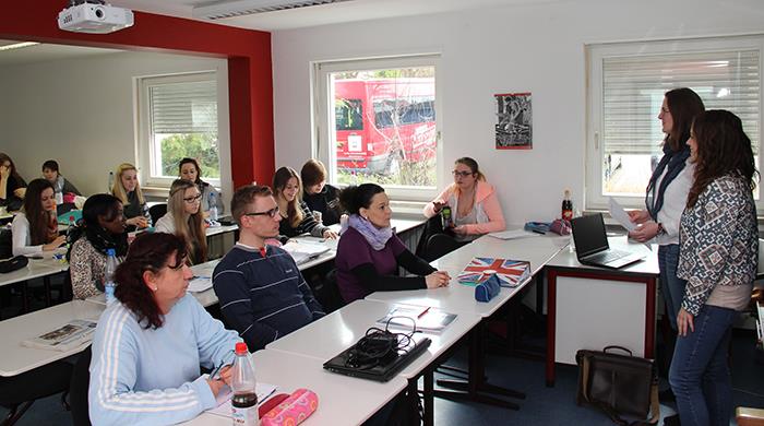 Zwei Studentinnen stehen vor einer Klasse in der Altenpflegeschule und unterrichten.