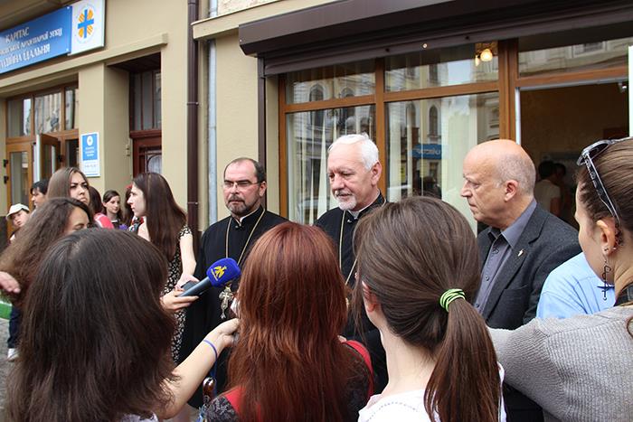 Viele Menschen stehen vor einer offenen Tür eines Gebäudes. 