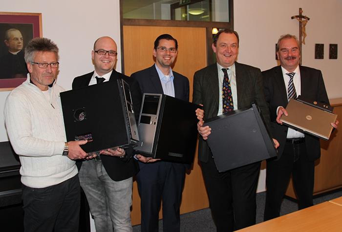 Im Geschäftshaus der Caritas halten 5 Männer die gespendeten PC vor sich. Es wurden 3 Standrechner und ein Laptop als Spende bereitgestellt. Die Männer freuen sich über diese gute Tat. 