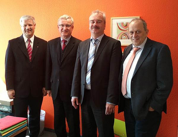 Die drei Caritasdirektoren haben Herr Dippel in ihre Mitte genommen. Sie tragen alle dunkle Anzüge und Krawatten. Vor den 4 Personen ist eine große Anzahl bunter Akten aufgestapelt. 