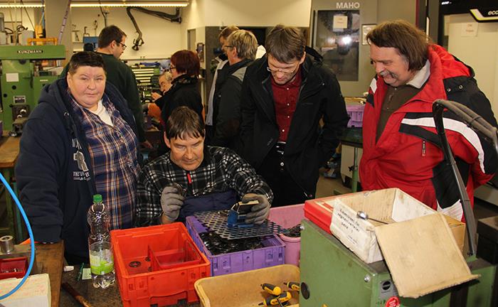 Die Gruppe ist in der Metallbearbeitung und schauen einem Mitarbeiter zu.