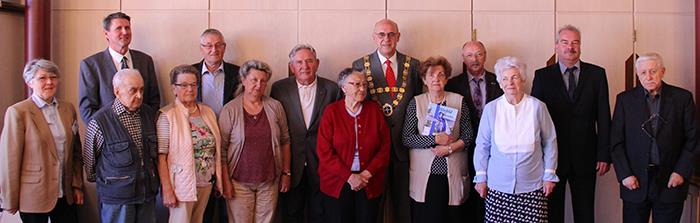 Die Gruppe der Anwesenden hat sich in 2 Reihen vor eine Wand im Rathaus zusammengestellt.