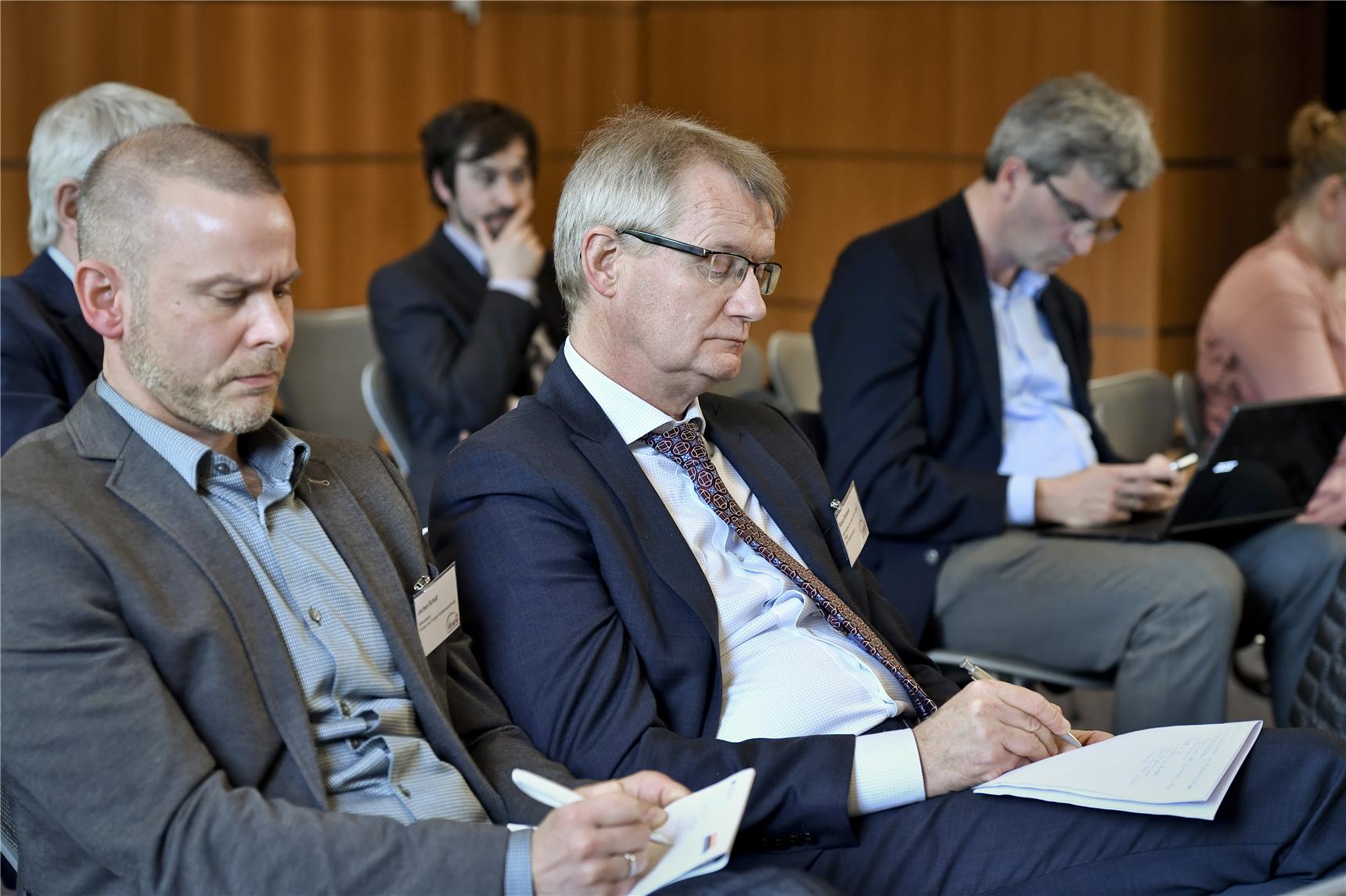 Personen auf einer Tagung die interessiert zuhören und mitschreiben