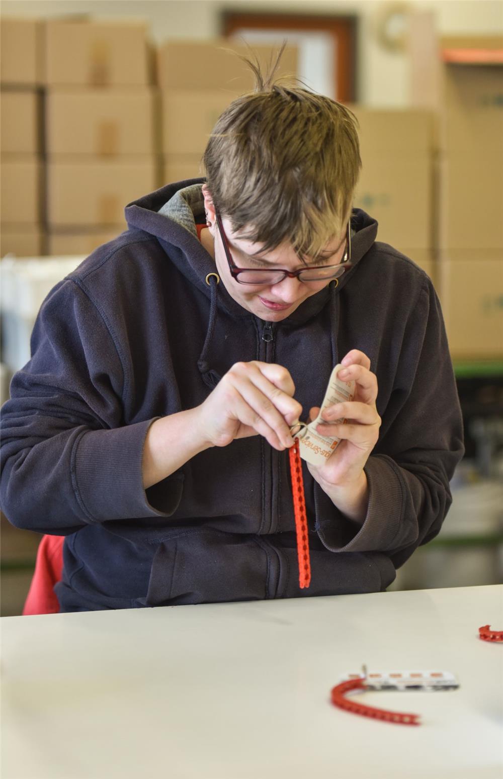 Eine junge Frau arbeitet in einem Beschäftigungsprojekt beziehungsweise einer Werkstatt für Menschen mit Behinderung.