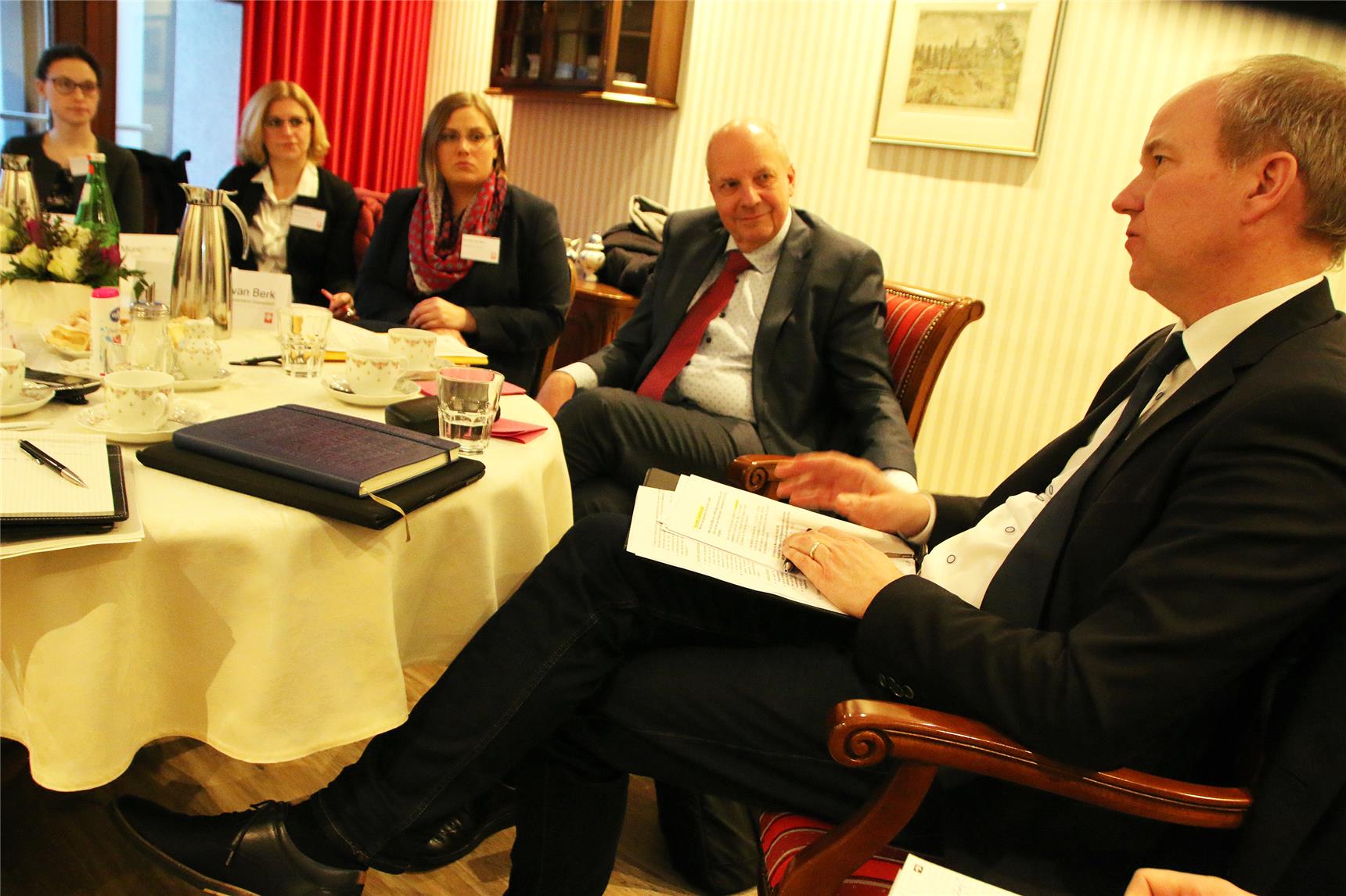 Das Foto zeigt eine kleine Gruppe von Menschen im Gespräch an einem Kaffeetisch