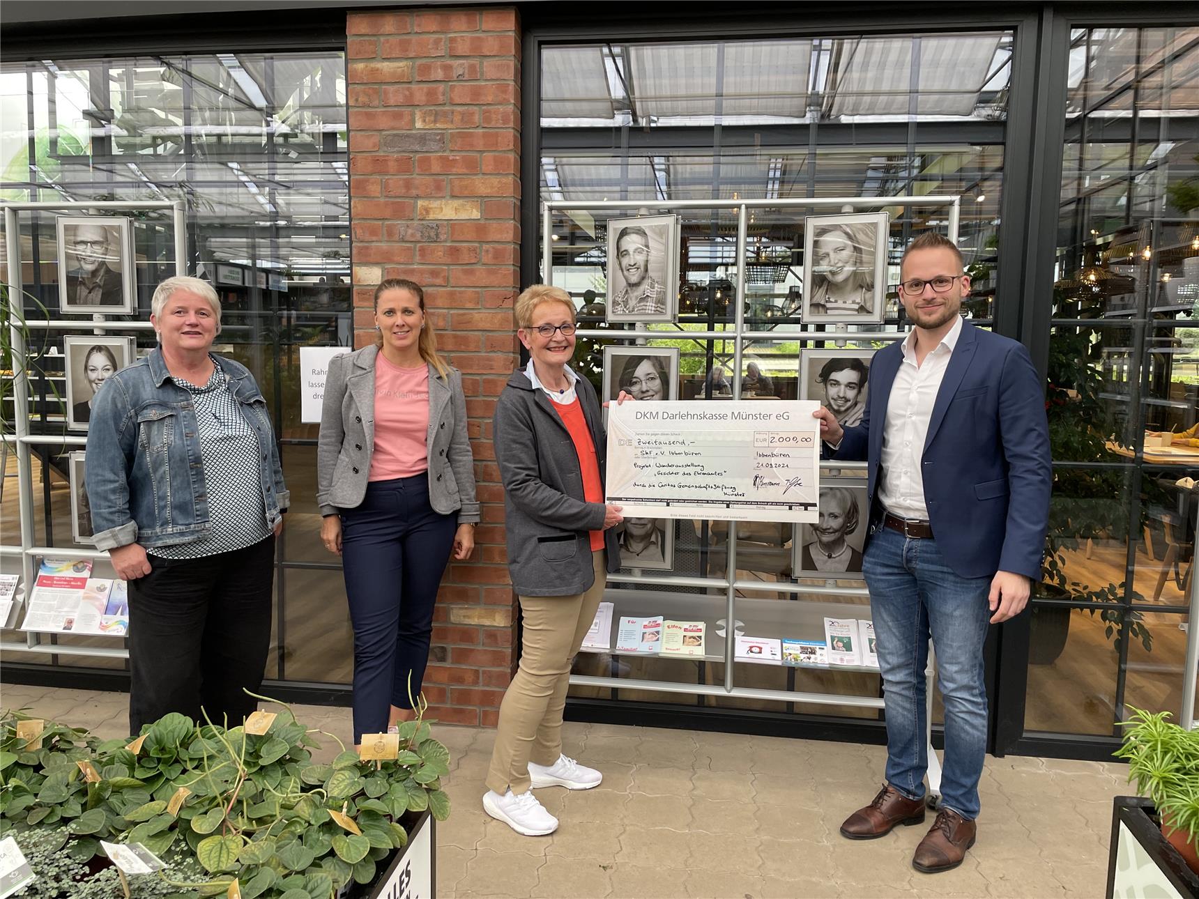 Das Foto zeigt eine Gruppe von Menschen, ein Mann übergibt einen Scheck an eine Frau.