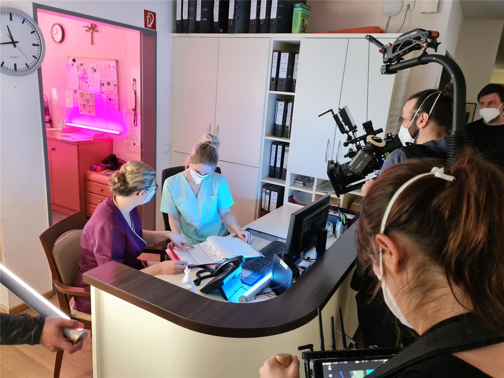 Das Foto zeigt ein Filmteam, das eine Szene an einem Empfangstisch dreht.