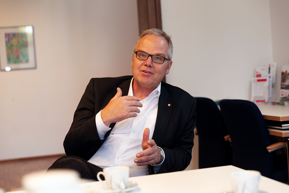 Porträt: Volker Brüggenjürgen, der an einem Besprechungstisch sitzt und gestikuliert