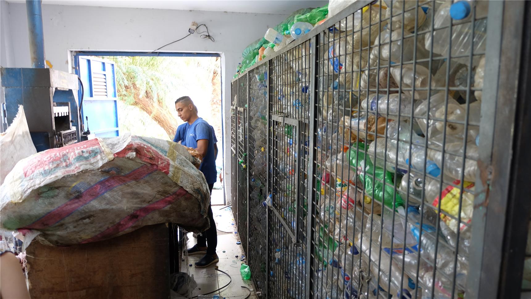 Gitterboxen mit Plastikflaschen vor einer Presse