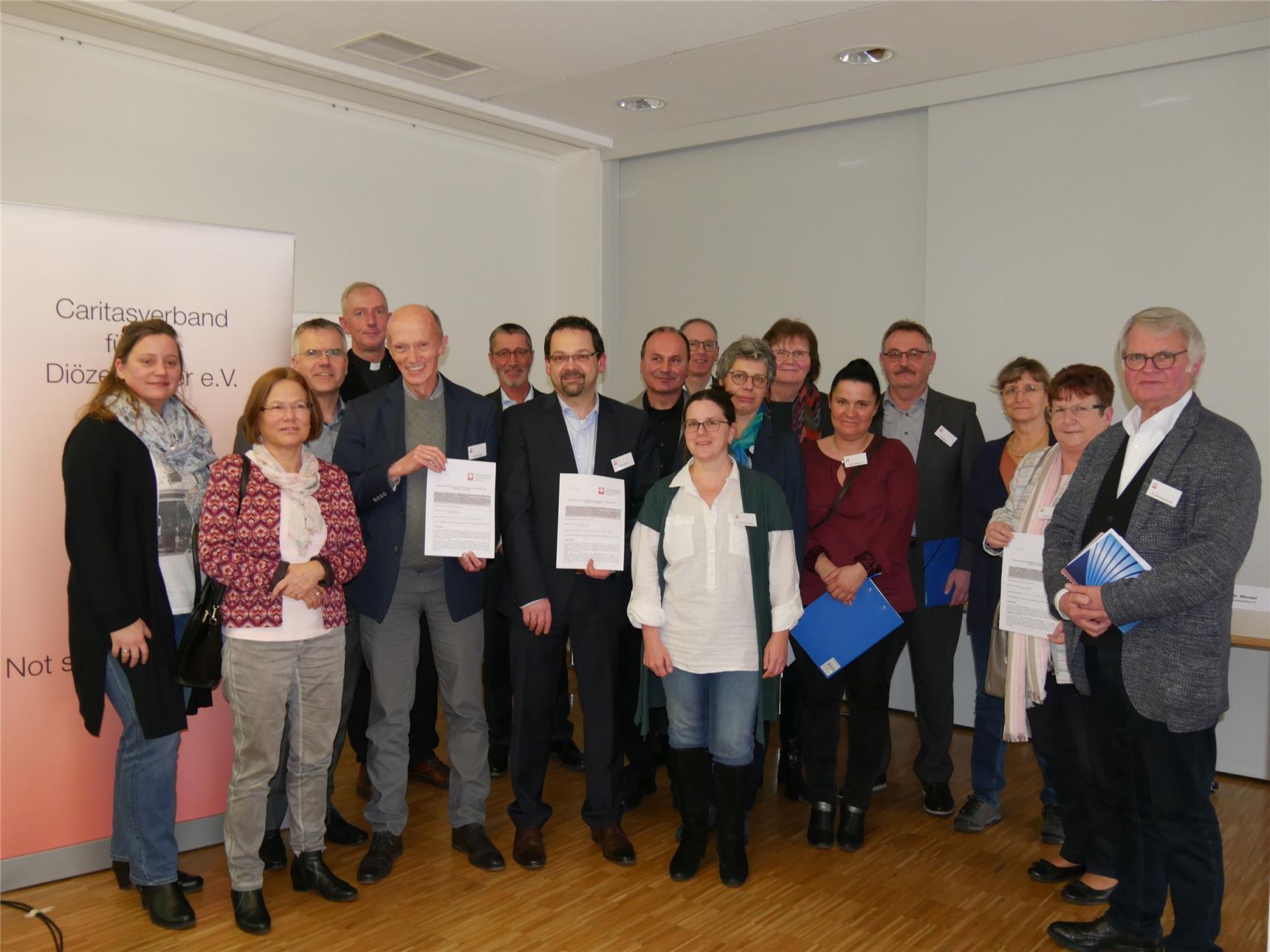 Die Projektbeteiligten stehen als Gruppe zusammen und präsentieren die unterschriebenen Vereinbarungen