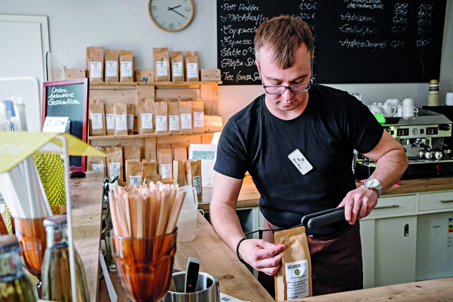 Ein Mitarbeiter der Goslarschen Höfe hantiert an der Kaffeetheke mit einer Kaffeebohnen-Packung.
