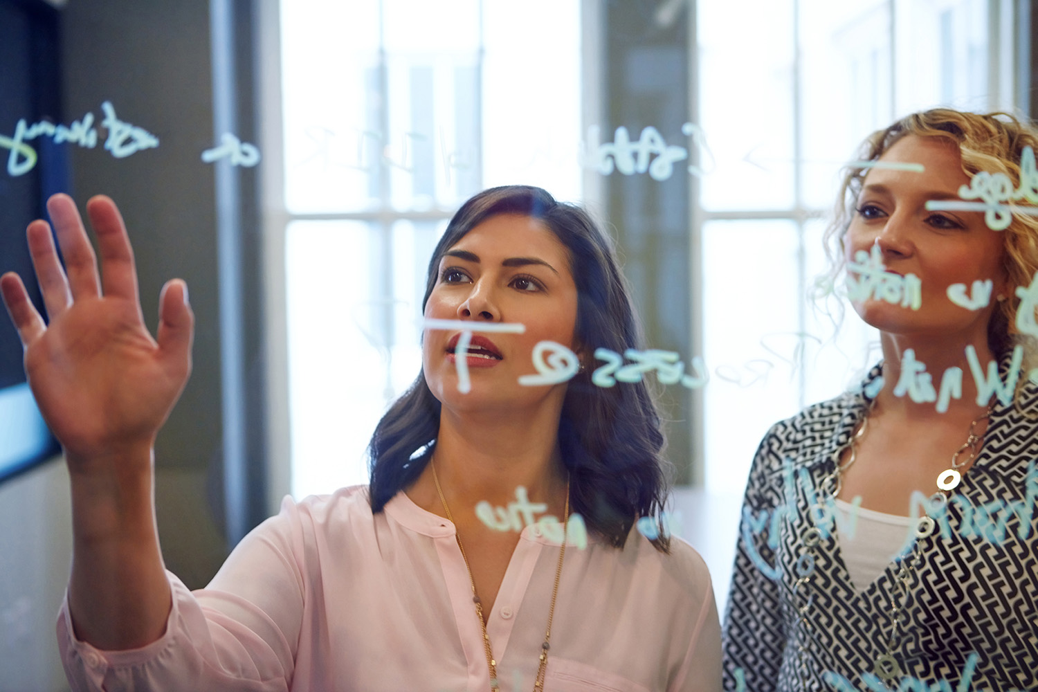 Zwei Frauen vor Glaswand in Büro