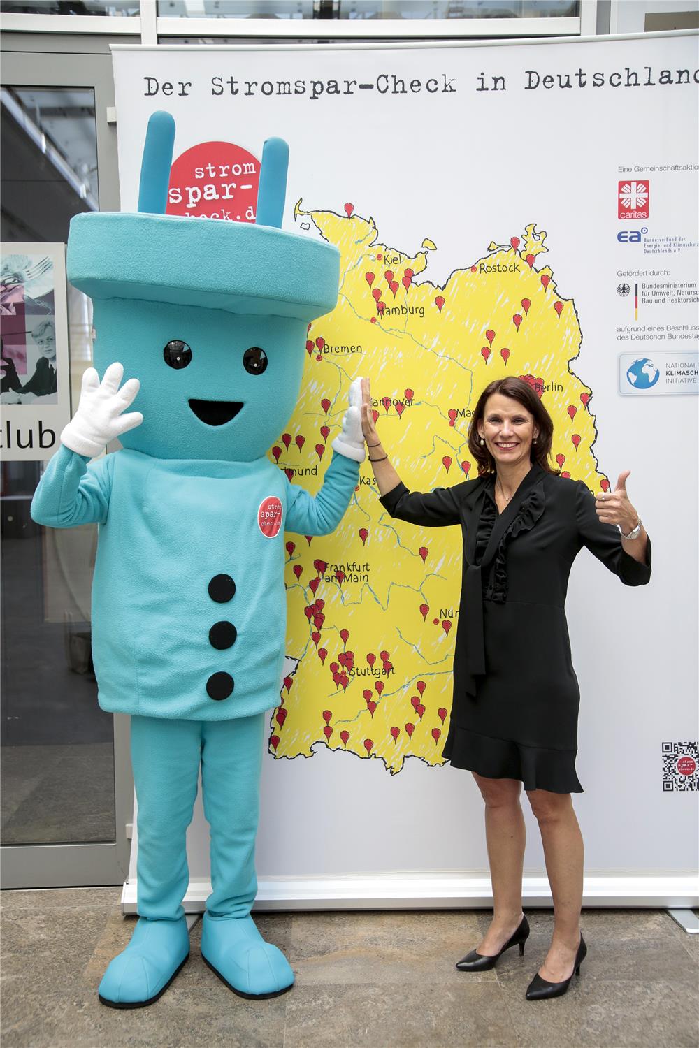 Ein Mensch, verkleidet als blauer Stromstecker gibt einer jungen Frau ein „High Five”.