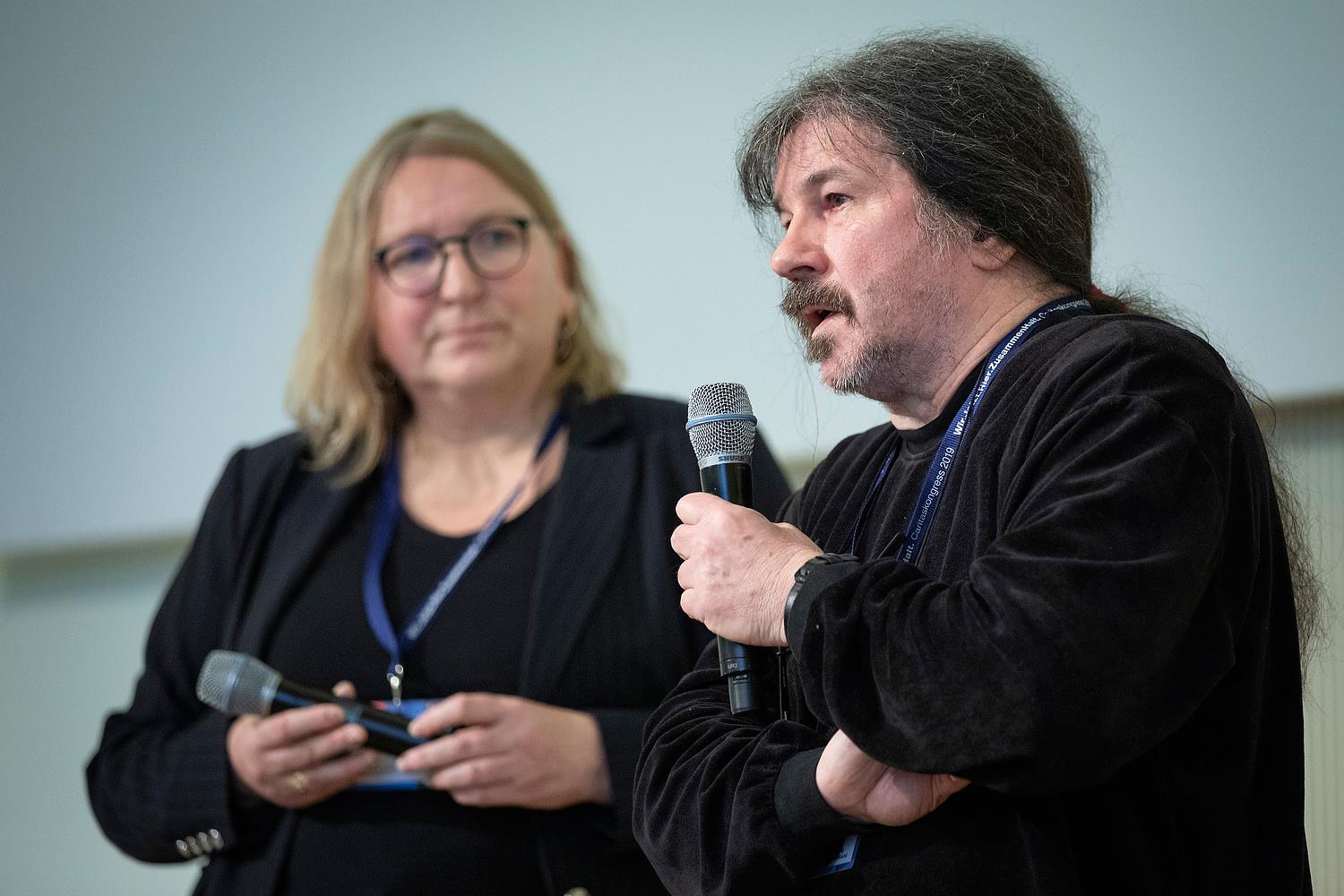 Frau und Mann mit Mikrofon auf einem Podium