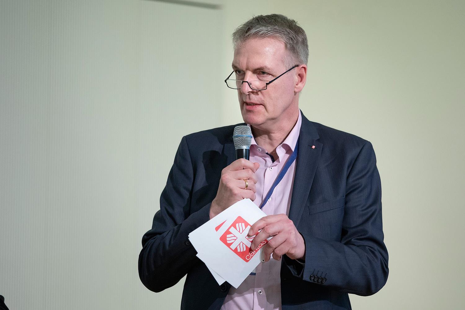 Mann moderiert mit Mikrofon und Handzetteln