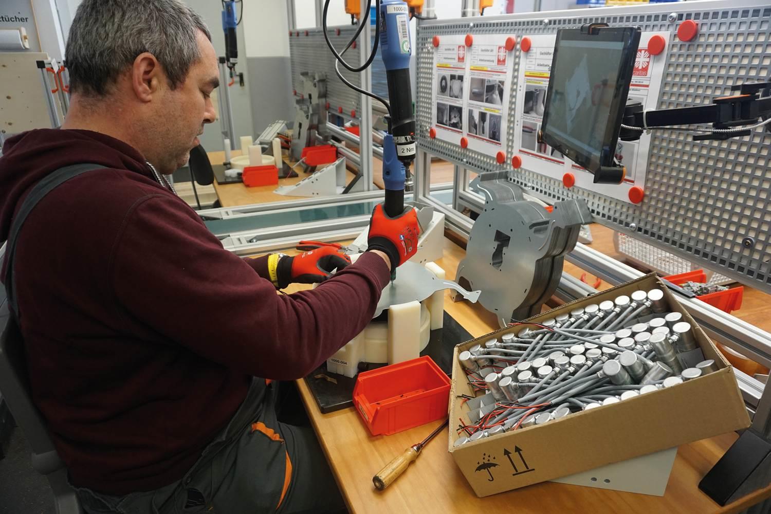 Mitarbeitender in einer Montagelinie einer Fabrik.