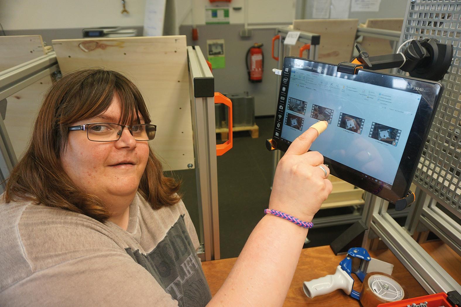 Melanie Esser zeigt auf ihren berührungsempfindlichen Bildschirm am Arbeitsplatz.