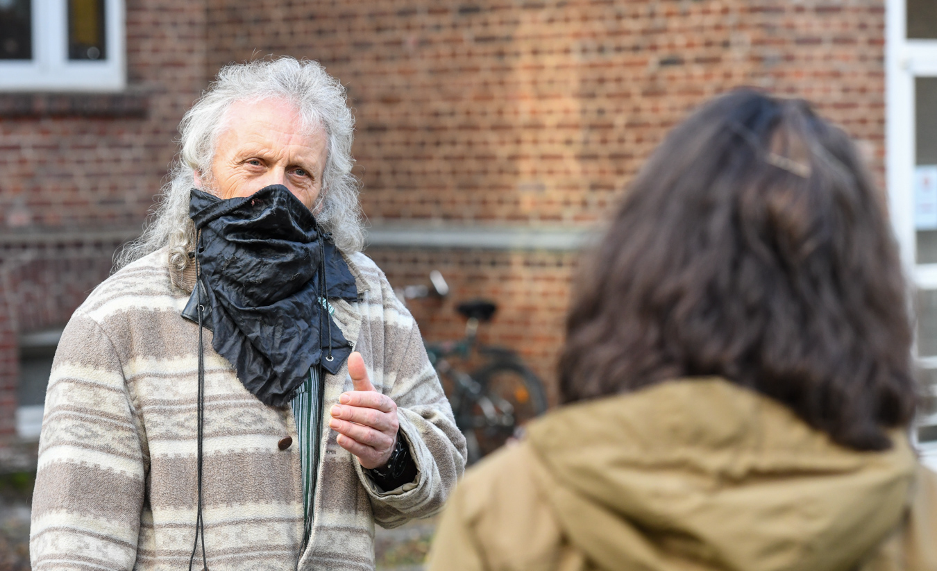 Ein Mann mit einer improvisierten Atemschutz-Maske spricht mit einer Frau.