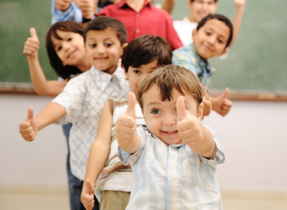 Kinder in einer Reihe die den Daumen lachend hoch halten