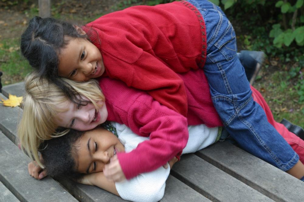 Spielende Kinder unterschiedlicher Nationen liegen auf einander