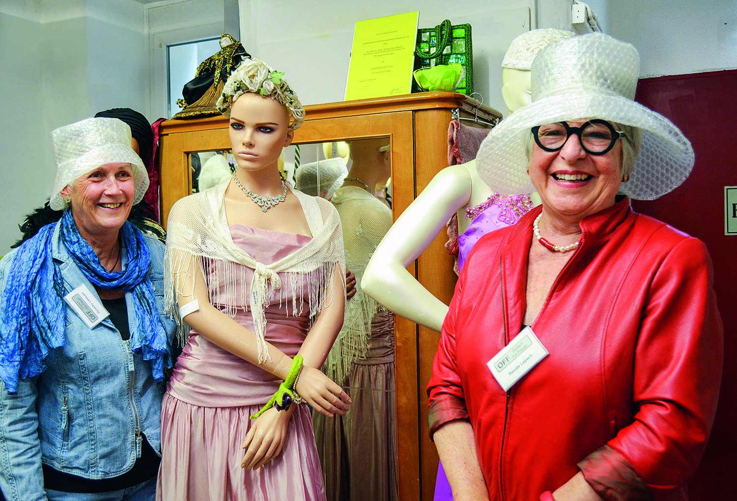 Die Vereinsmitarbeiterinnen Lehmann und Lepach tragen modisch geschneiderte Regenhüte aus Blisterfolie.