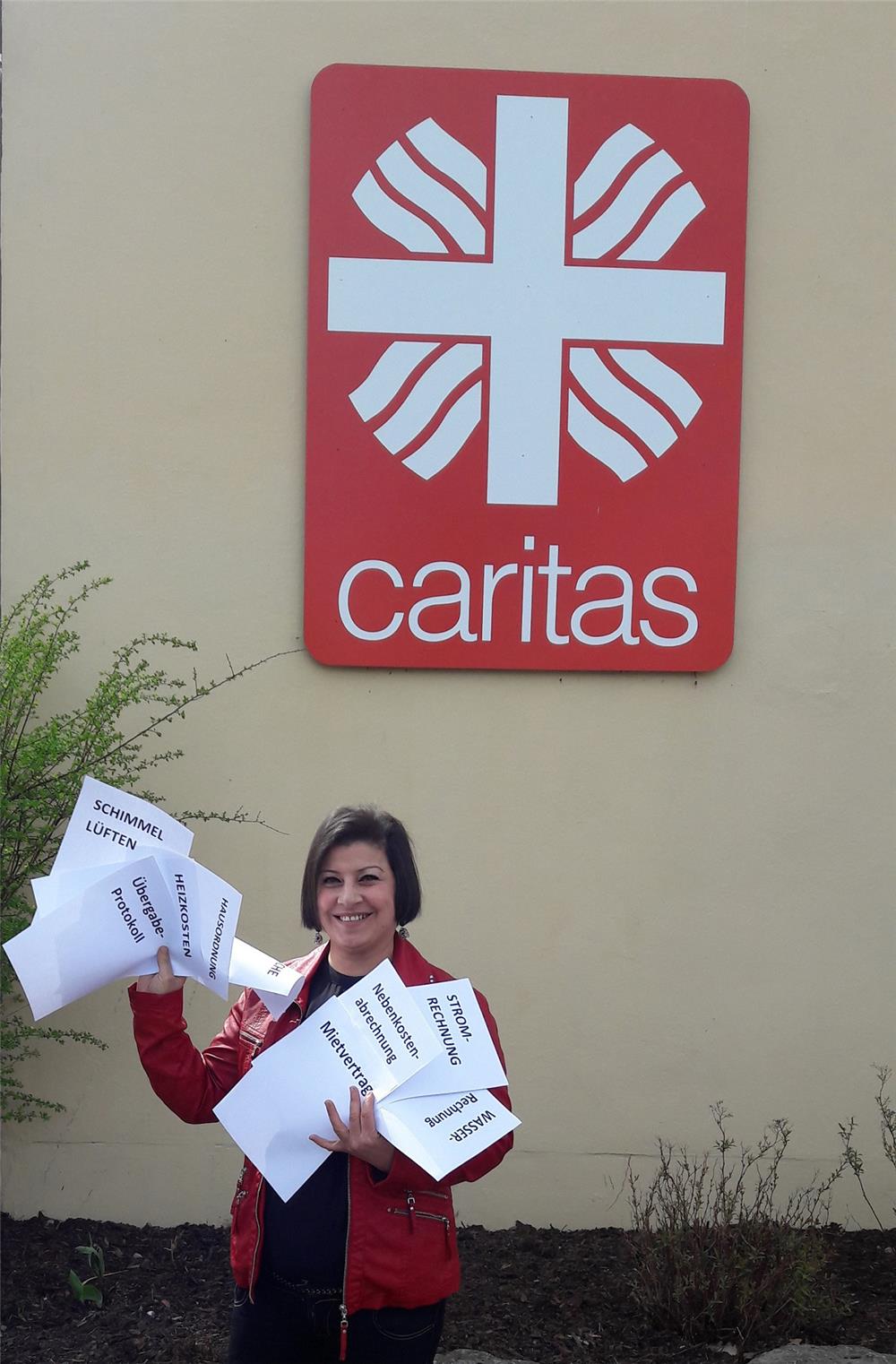 Frau mit Blättern in der Hand vor Caritas-Logo