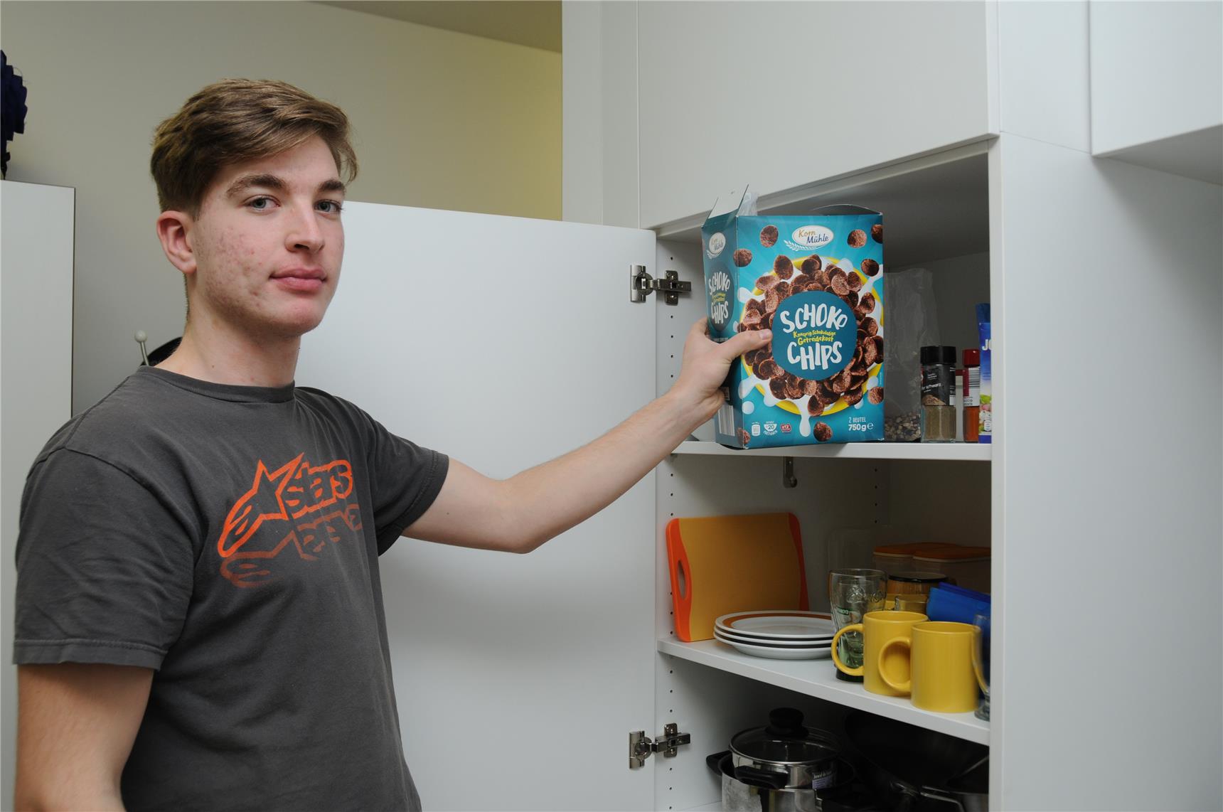 Junge holt Müsli aus Schrank