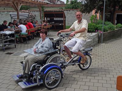 Mann fährt alte Frau in elektrisch unterstütztem Rollstuhltransporter