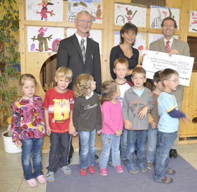 Scheckübergabe an Verantwortliche, davor Kinder