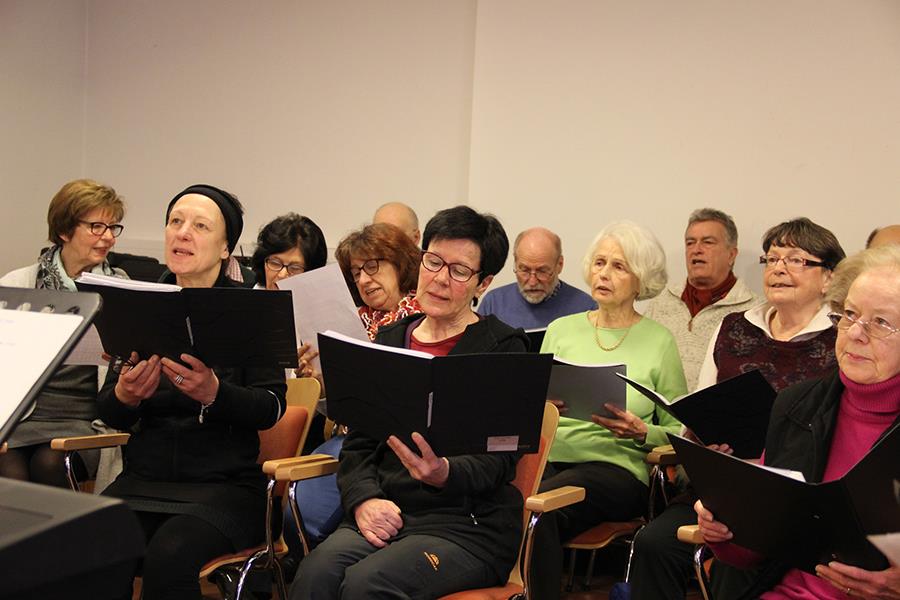 Die Sänger sitzen im Raum und schauen auf ihre Noten.