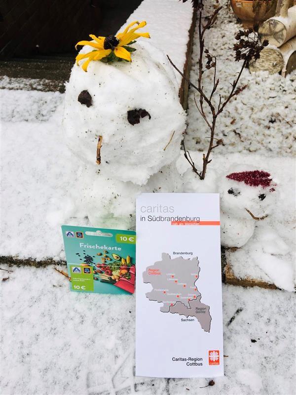 Schneemann mit Flyer der Caritas-Region Cottbus