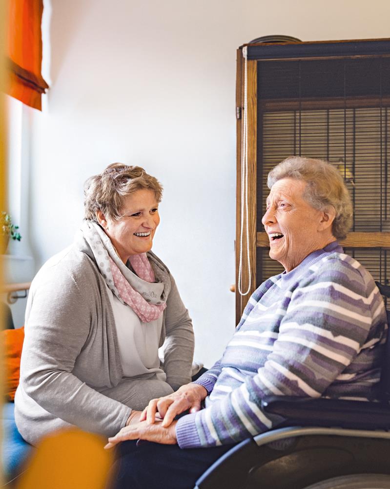 Zwei lachende Frauen sitzen zusammen